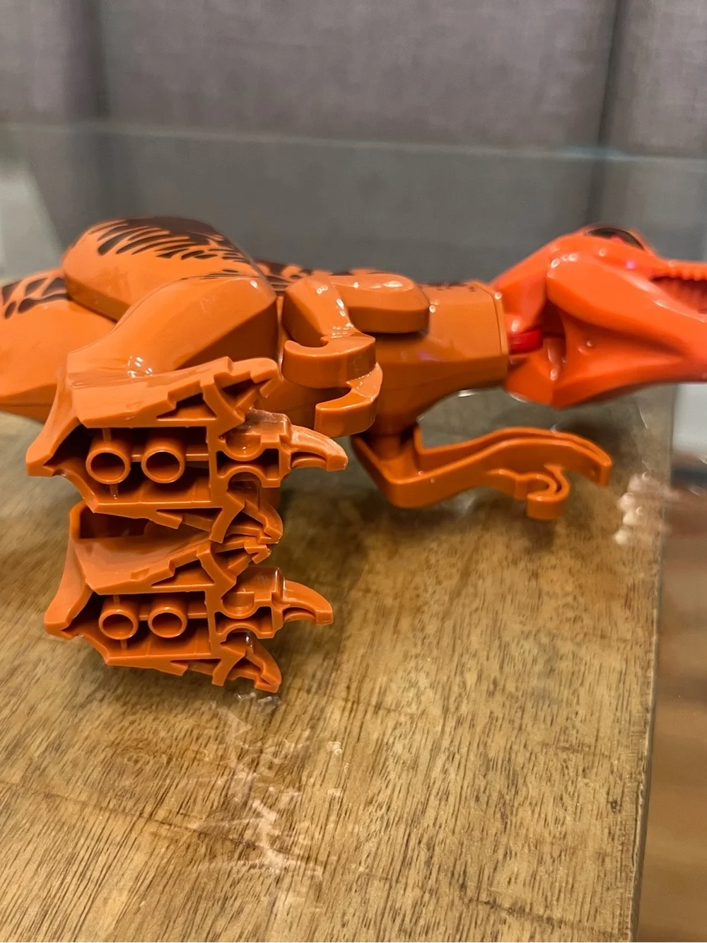 orange-and-brown molded plastic Tyrannosaurus Rex dinosaur makes noise building